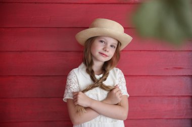 Kızıl saçlı kız beyaz bir şapka kırmızı ahşap duvar arka plan üzerinde elbise
