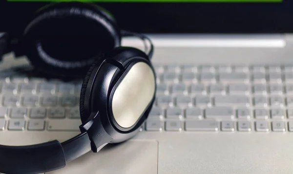 Headphones on a laptop. Big black headphones. Headphones closed.  Headphones on a computer keyboard. The concept of remote work and rest during quarantine. Freelancer workplace