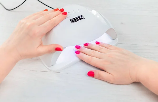 Manicure at home. Manicure process in lamp, woman hand