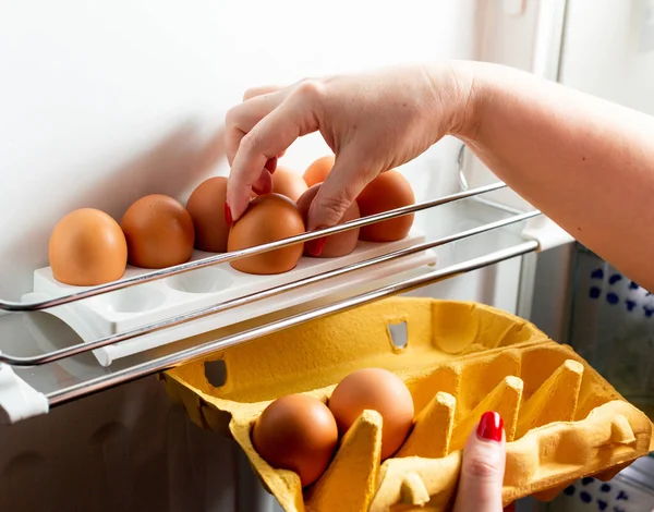 Buzdolabındaki karton paketlerden elle tavuk yumurtası koleksiyonu. Organik tavuk yumurtaları buzdolabında taze kalsın. Tepside kahverengi yumurtalar. 