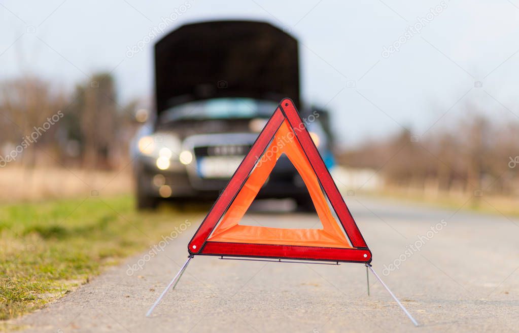 breakdown triangle stands near a broken car