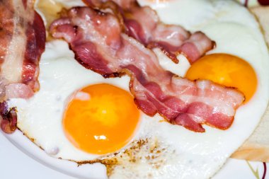 lezzetli domuz pastırması şeritler üzerinde kızarmış yumurta yatıyor