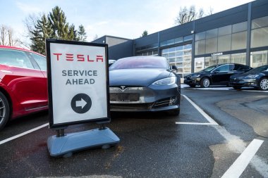 FUERTH / GERMANY - MARCH 4, 2018: Tesla service sign near a car dealer. Tesla, Inc. is an American company that specializes in electric automotives, energy storage and solar panel manufacturing. clipart