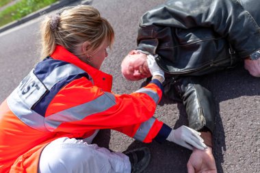 Alman sağlık görevlisi yaralı bir bisikletçinin kan basıncı kontrol edin. Rettungsdienst ambulans servisine Alman bir kelimedir.
