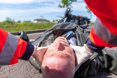 Alman sağlık görevlisi bir kask yaralı bir bisikletçinin kaldırır. Rettungsdienst ambulans servisine Alman bir kelimedir.