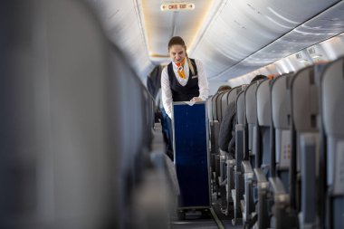 Antalya / Türkiye - 24 Ocak 2020: Airlines Sunexpress hostesi, yolcu kabininden bir servis arabasıyla geçiyor.