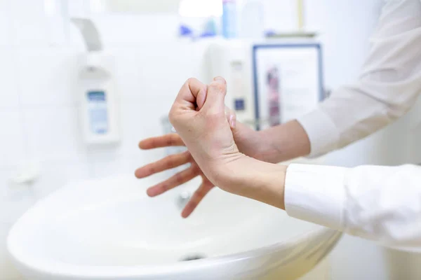 A nurse disinfects her hands in a hospital room