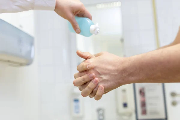 Nurse disinfects a patients hand at a sink