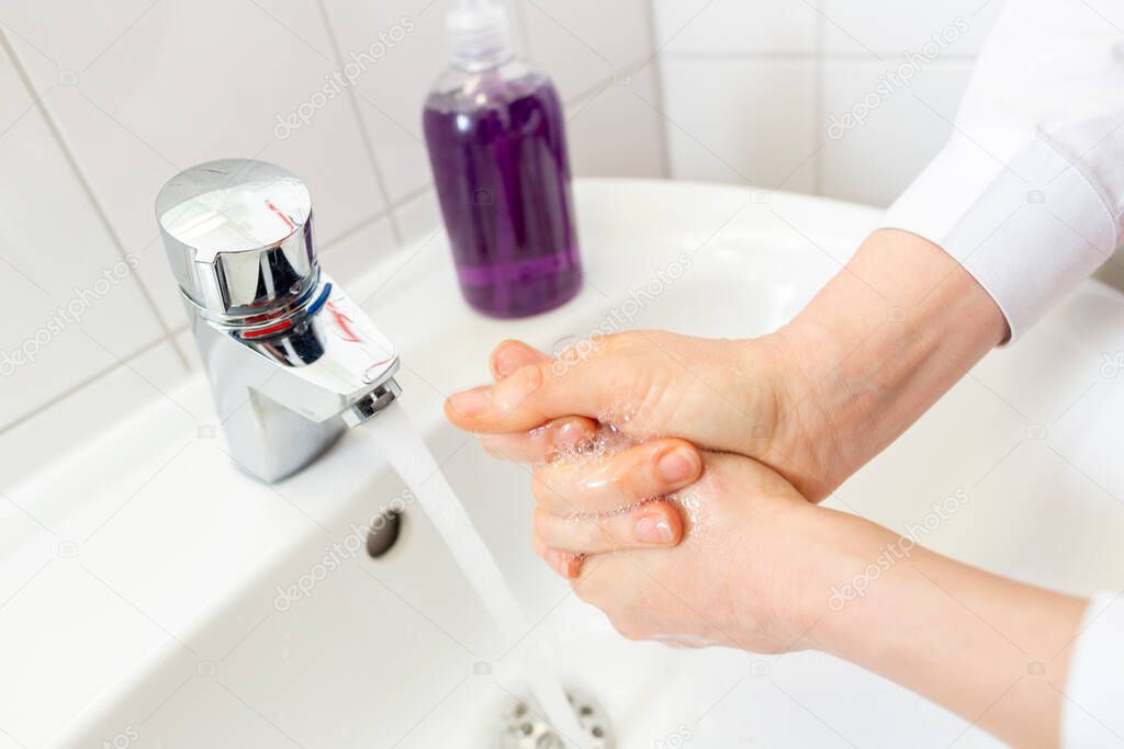a woman washes her hands with soap
