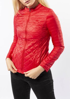 Kırmızı ceketli sarışın kız siyah kot pantolon ve beyaz arka planda spor ayakkabıları.