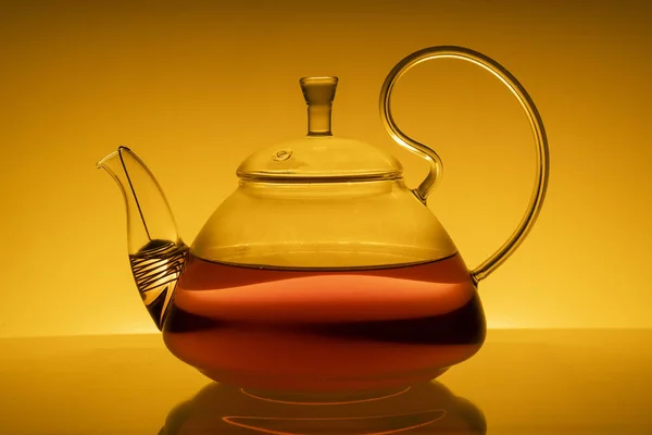 黄色の背景にお茶が入ったグラスティーポット反射して黄色の背景にガラスティーポット — ストック写真