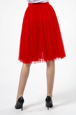 Beyaz arka planda yüksek topuklu kırmızı etekli bir kız.