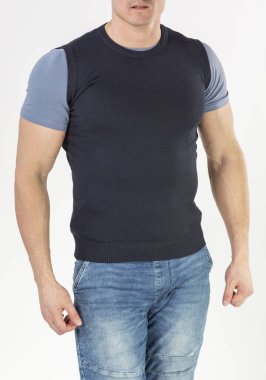 Örgü bir yelek ve beyaz arka planda mavi kot giyen bir adam.