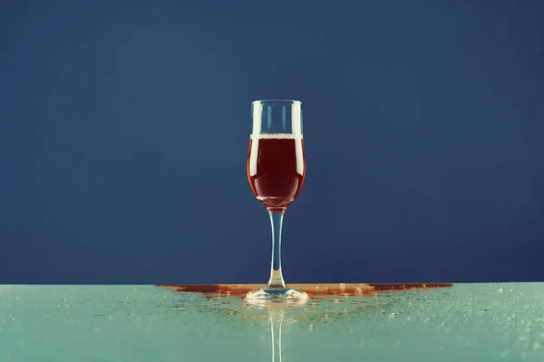 Vin rouge dans un verre sur fond bleu — Photo