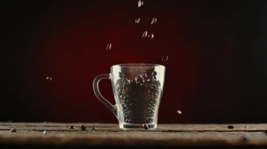 Kahve çekirdekleri ahşap bir masada fincana düşer.