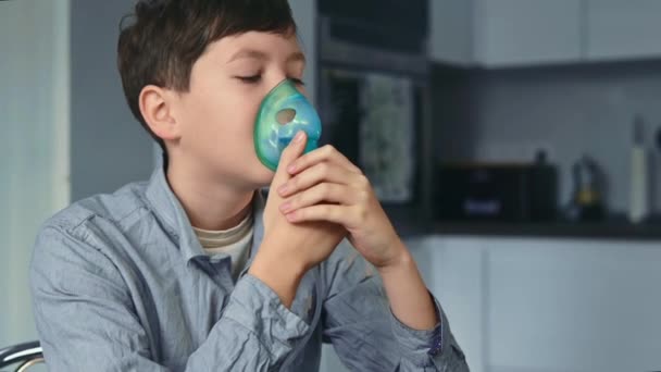 Traitement de l'asthme, le garçon respire par un inhalateur. Debout dans la cuisine — Video