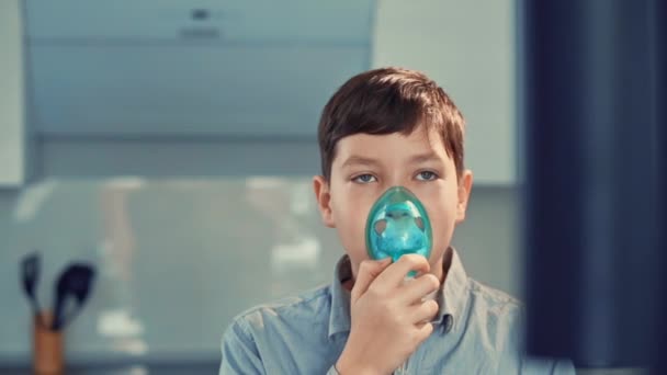 Treatment for asthma, the boy breathes through an inhaler. Standing in the kitchen — 비디오