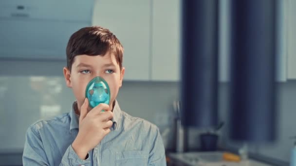 Behandeling van astma, de jongen ademt via een inhalator. Staande in de keuken — Stockvideo