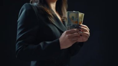 Yakın plan, genç kadın işadamı siyah arkaplandan bir dolarlık banknot seçiyor. 4k