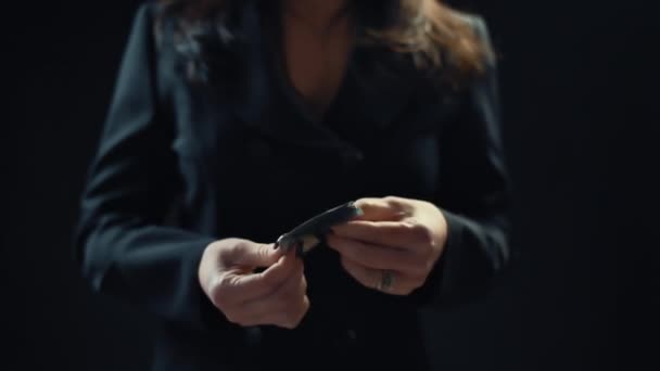 Closeup, young female businessman looking at money with two hands, on black background. Slow motion. 4k — Stock Video