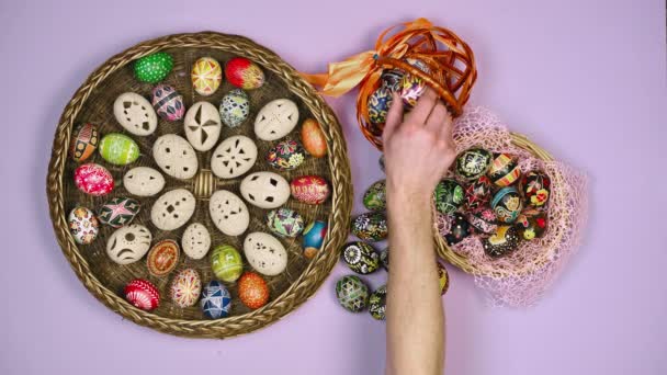 Hands putting in basket with Easter eggs near basket on pink background. Easter is holy. 4k — ストック動画