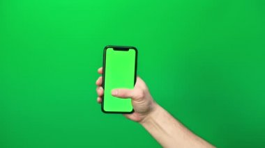 Eldeki telefon yeşil arka planda izole edilmiş. Telefon ekranı - yeşil krom anahtar, arka plan yeşil krom anahtar. Mobil reklamlar, tanıtımlar için çerçeve.