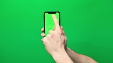 Eldeki telefon yeşil arka planda izole edilmiş. Telefon ekranı - yeşil krom anahtar, arka plan yeşil krom anahtar. Mobil reklamlar, tanıtımlar için çerçeve.