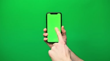 Eldeki telefon yeşil arka planda izole edilmiş. Telefon ekranı - yeşil krom anahtar, arka plan yeşil krom anahtar. Mobil reklamlar, tanıtımlar için çerçeve.