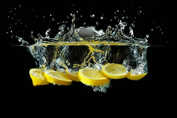 Siyah arka planda suya atılmış limon dilimleri. Sualtı ateşi.