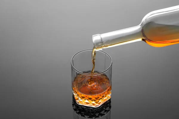 Barmen, gri arka planda bardağa viski dolduruyor, soğuk atmosfer, viskiyle dinlenme zamanı.
