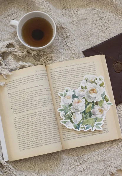 Garden roses flower painted with watercolor, paintbrush, around the books and tea. Overhead view. Flat lay, top view.