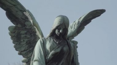 Bir güneşli bir bahar gününde bir melek ile 20 yüzyıldan eski mezar taşı. Angel'dan bulanıklık. 4k Slog3. Yakın çekim.