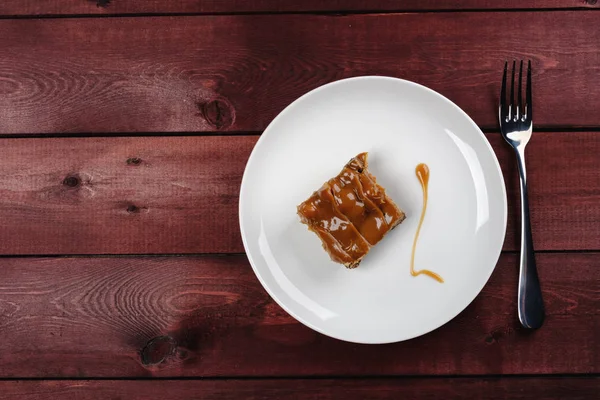 bir parça çikolatalı brownie ve beyaz tabakta karamel sos. Üstten Görünüm