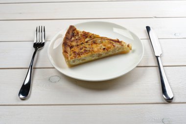 Bir beyaz tahta masanın üzerinde yatan çatal ile beyaz tabakta pasta