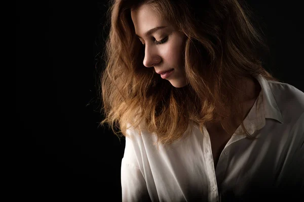 Close-up van studio portret in profiel van jonge lachende vrouw in witte blouse op zwarte achtergrond — Stockfoto