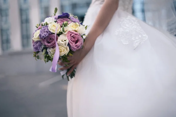 Bruiloft boeket van paarse en witte bloemen in handen van de bruid — Stockfoto