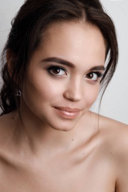 Bir genç kız esmer kahverengi gözleri ve yumuşak doğal makyaj portresi. Gülümseyen ve kameraya bakarak kız