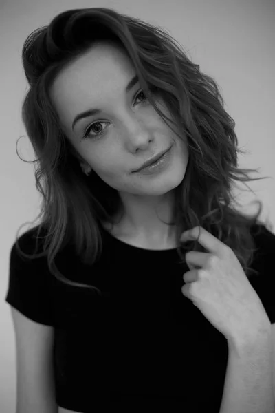 Retrato de una joven con una camiseta negra mirando a la cámara. Foto vertical en blanco y negro — Foto de Stock