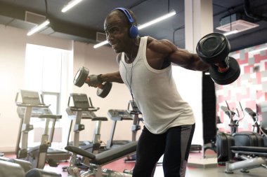 zor iş. Kaslı zenci spor salonunda dumbbells ile yapıyor