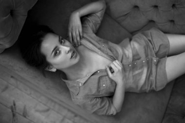 Siyah ve beyaz bir gömlek koltukta yatan genç bir esmer portresi