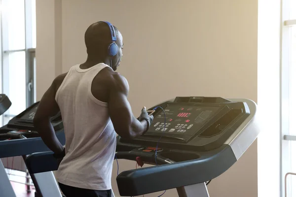 Joven en ropa deportiva corriendo en la cinta de correr en el gimnasio — Foto de Stock