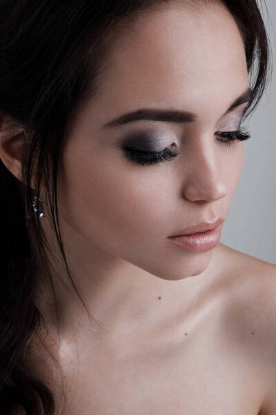 Портрет брюнетки крупным планом с вечерним макияжем с закрытыми глазами
