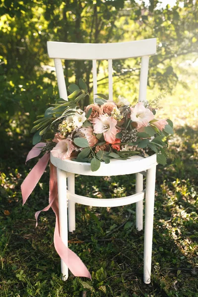 Ramo nupcial de flores rosadas y vegetación, se encuentra en la silla de madera blanca vintage — Foto de Stock