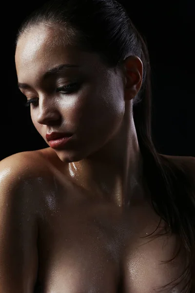 Mooi meisje met een naakt make-up en natte haren en huid. Het gezicht van de schoonheid. Foto genomen in de studio op een zwarte achtergrond. — Stockfoto