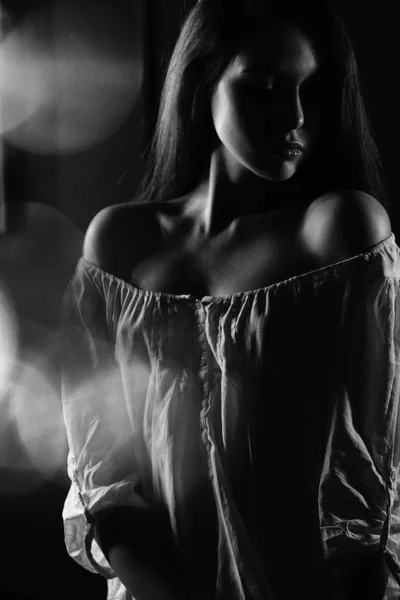 Black and white silhouette portrait of a young girl in a white blouse with bare shoulders.