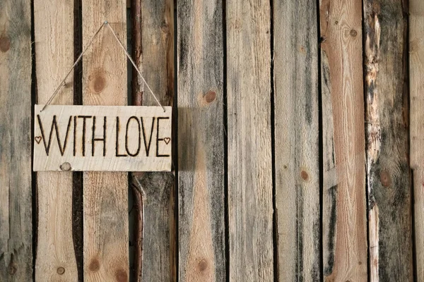 Plaque with the inscription WITH LOVE hangs to the left on the background of wooden wall. — Stock Photo, Image