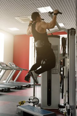 Bir adam siyah bir tişört ve pantolon bir halter kemer ile koşu bandı üzerinde arka görüş sıkılır