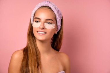 Saçları açık, omuzları çıplak ve göz altı yamalı bir kızın yakın portresi..