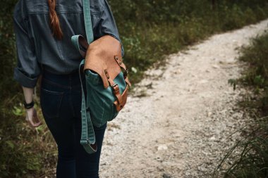 Sırt çantasında sırt çantasıyla bir yolda yürüyen bir kızın sırtından yakın çekim, sırt çantasına odaklan..