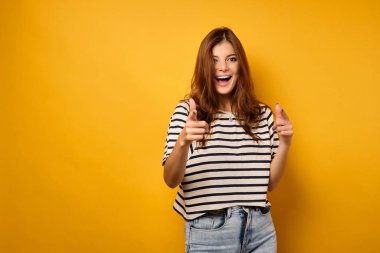 Çizgili tişörtlü güzel bir esmer, önünde uzanmış işaret parmaklarıyla el ele tutuşurken gülüyor. Yüze odaklan..